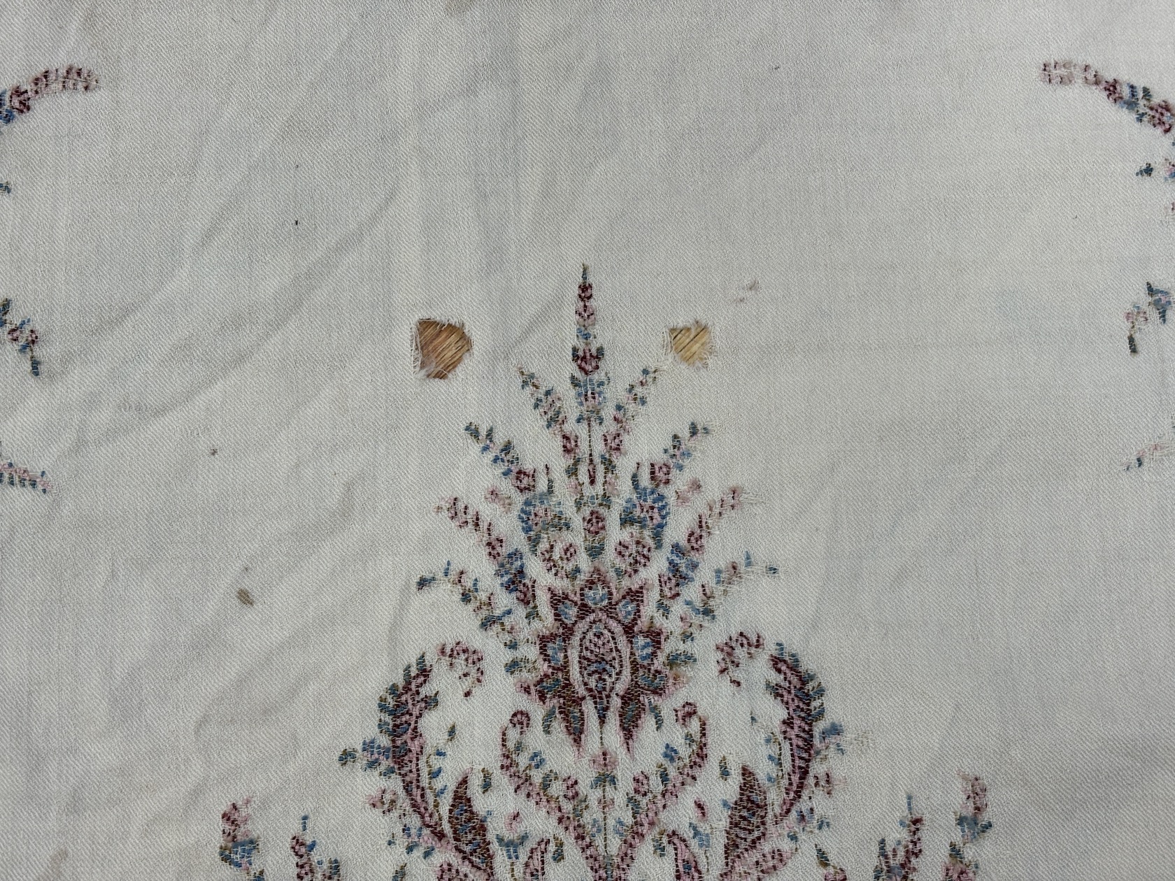 A late 19th century wool woven Paisley shawl with cream central cartouche (some damage)